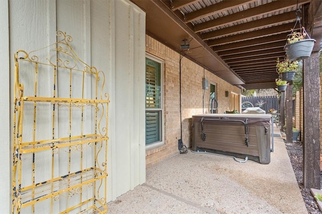 view of side of property featuring a hot tub and a patio area