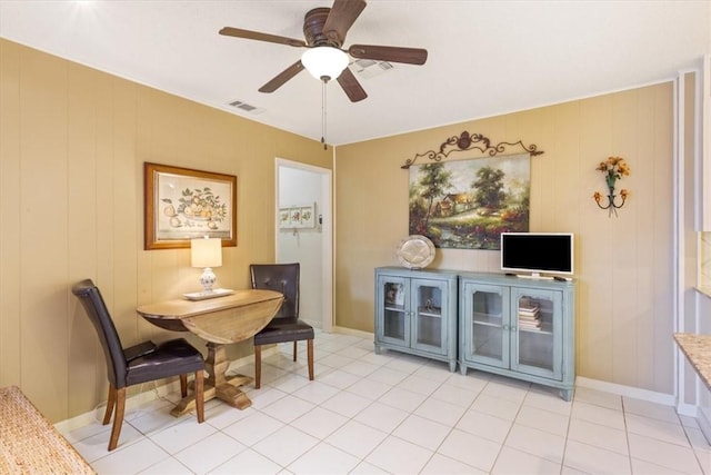 dining area featuring light tile patterned floors, ceiling fan, and wood walls