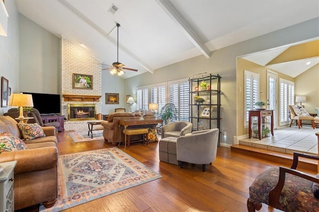 living room with hardwood / wood-style floors, a wealth of natural light, a fireplace, and beamed ceiling