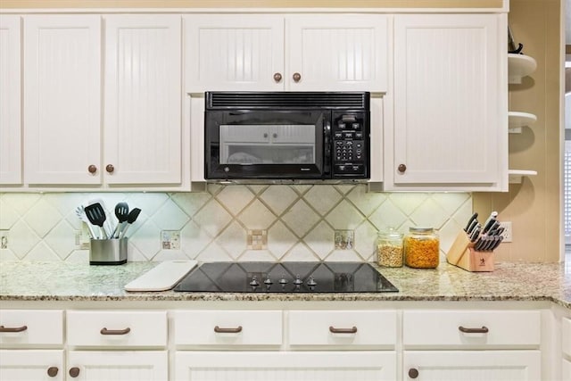 kitchen featuring tasteful backsplash, white cabinets, light stone countertops, and black appliances