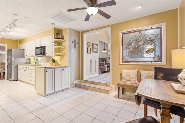 kitchen featuring stainless steel refrigerator, white cabinetry, backsplash, light tile patterned floors, and ceiling fan