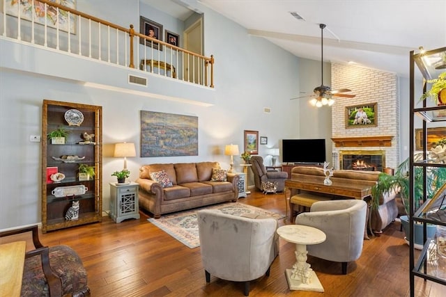 living room featuring hardwood / wood-style flooring, a fireplace, high vaulted ceiling, and ceiling fan