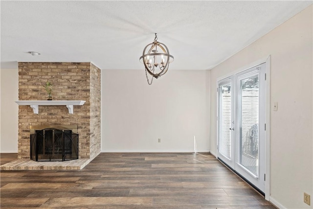 unfurnished living room featuring a fireplace, a textured ceiling, a chandelier, and dark wood-type flooring