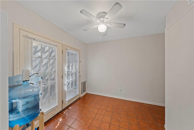 doorway featuring tile patterned flooring, ceiling fan, and wood walls