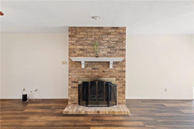 unfurnished living room featuring dark wood-type flooring and a brick fireplace