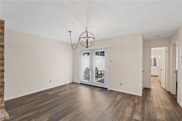 spare room with a notable chandelier, dark hardwood / wood-style floors, and a textured ceiling