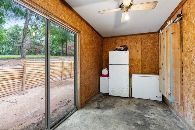 interior space featuring concrete floors, white fridge, ceiling fan, and ornamental molding