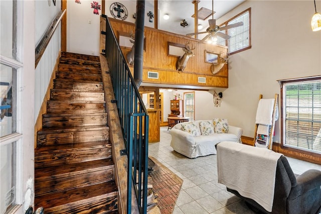 staircase with tile patterned flooring, ceiling fan, and a towering ceiling