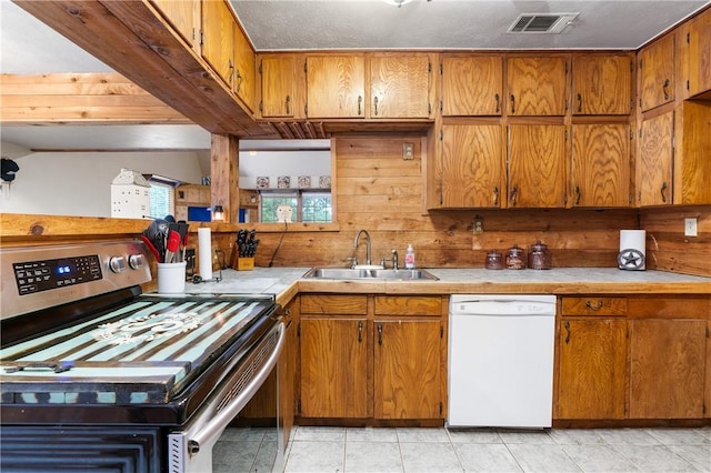 kitchen featuring white dishwasher, stainless steel electric range oven, sink, and light tile patterned floors