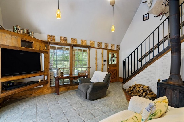 living room with a wood stove, high vaulted ceiling, and light tile patterned flooring