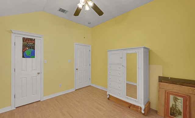 unfurnished bedroom featuring a ceiling fan, wood finished floors, visible vents, baseboards, and lofted ceiling