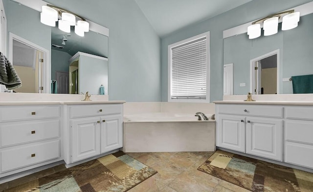 full bathroom featuring vaulted ceiling, two vanities, a garden tub, and a sink