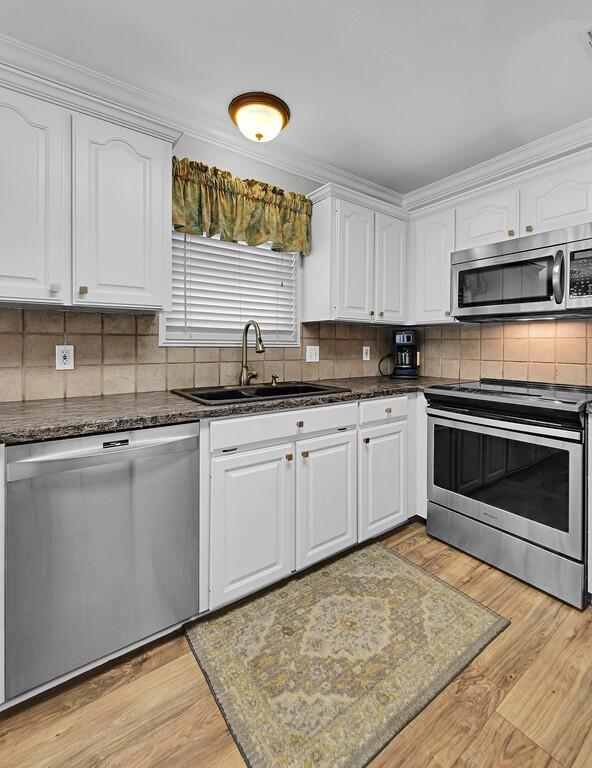 kitchen with white cabinetry, light wood-style flooring, appliances with stainless steel finishes, and a sink