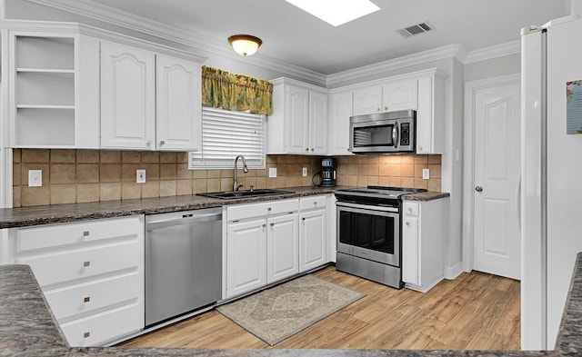 kitchen with appliances with stainless steel finishes, white cabinetry, light wood-type flooring, and a sink