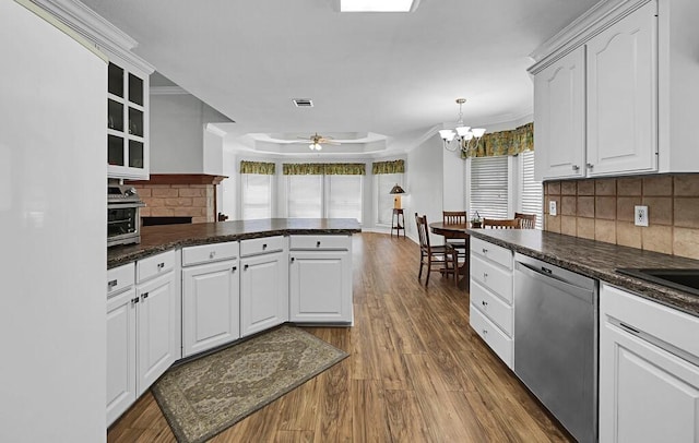 kitchen with dark countertops, stainless steel dishwasher, a peninsula, and dark wood-style floors