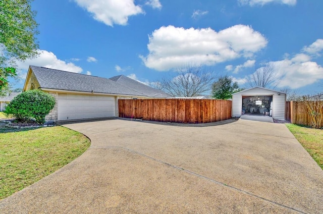 view of front of house with a front yard, fence, an attached garage, a shingled roof, and concrete driveway