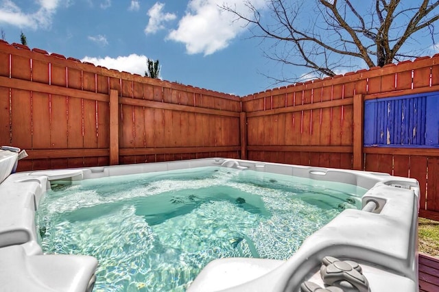 view of pool with a hot tub and fence