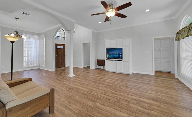 interior space featuring visible vents, ornamental molding, a ceiling fan, arched walkways, and light wood-style floors