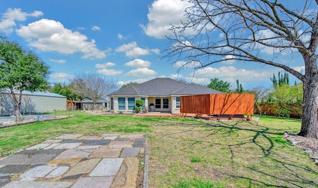 rear view of house with a lawn and fence