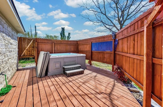 wooden terrace with a hot tub and a fenced backyard