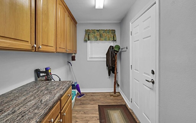 clothes washing area with baseboards and dark wood-style floors