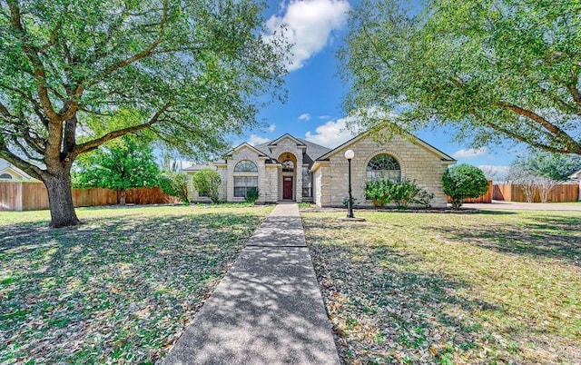 view of front of property with a front lawn, fence, and stone siding