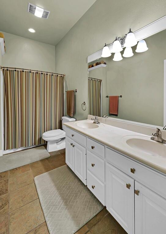 full bathroom with a sink, visible vents, toilet, and double vanity