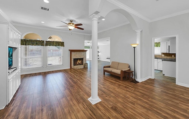 unfurnished living room featuring decorative columns, dark wood-type flooring, a brick fireplace, and a ceiling fan