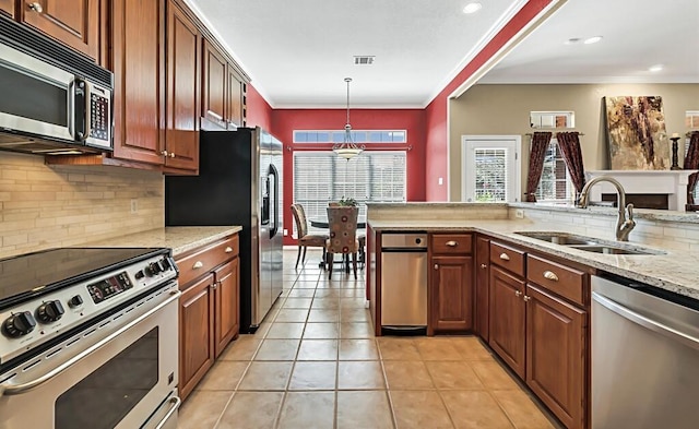 kitchen with sink, stainless steel appliances, backsplash, pendant lighting, and light tile patterned flooring