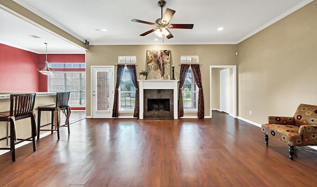 living room with ceiling fan, dark hardwood / wood-style flooring, crown molding, and a tile fireplace