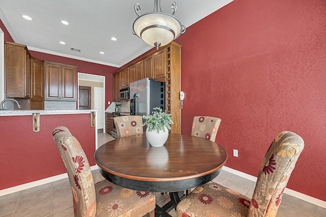 tiled dining room featuring sink and ornamental molding