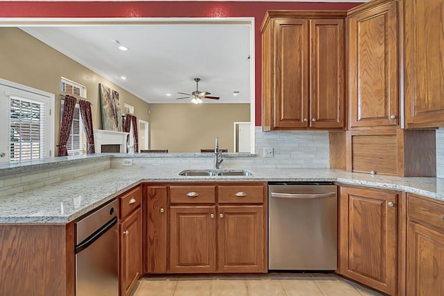 kitchen featuring decorative backsplash, light stone counters, stainless steel dishwasher, ceiling fan, and sink