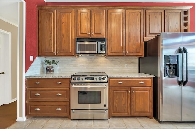 kitchen with light tile patterned floors, light stone countertops, and appliances with stainless steel finishes