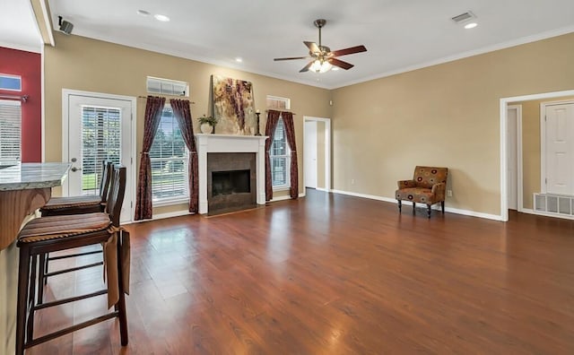 unfurnished living room with ceiling fan, ornamental molding, and dark wood-type flooring