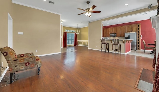 living room with ceiling fan with notable chandelier, light hardwood / wood-style flooring, and ornamental molding