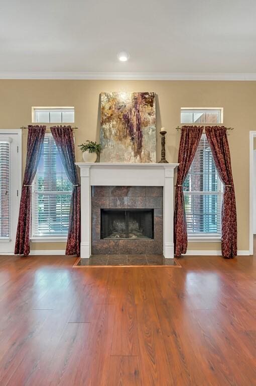 unfurnished living room with a fireplace, wood-type flooring, and ornamental molding