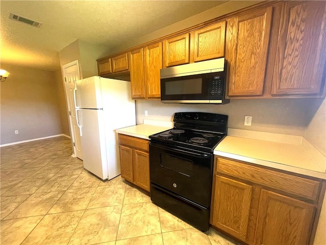 kitchen with electric range, white fridge, light tile patterned floors, and a textured ceiling