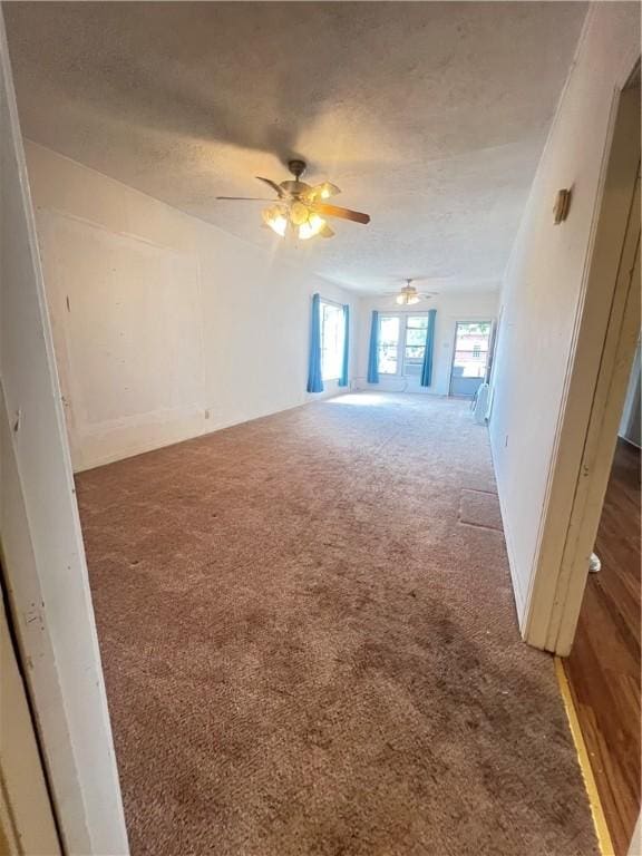 empty room with ceiling fan, a textured ceiling, and dark colored carpet