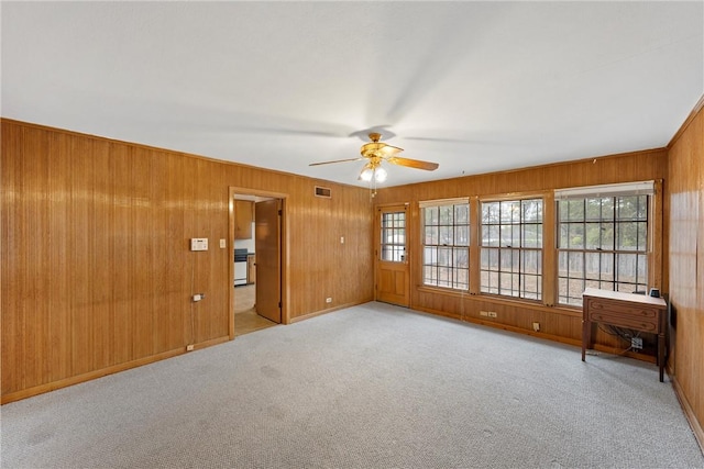 carpeted spare room featuring ceiling fan and wood walls