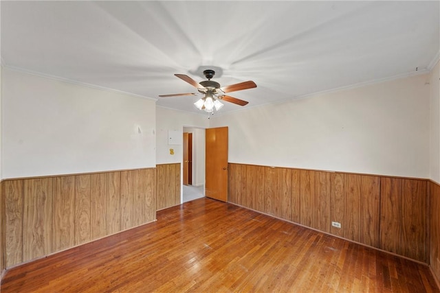 unfurnished room with crown molding, hardwood / wood-style floors, ceiling fan, and wood walls