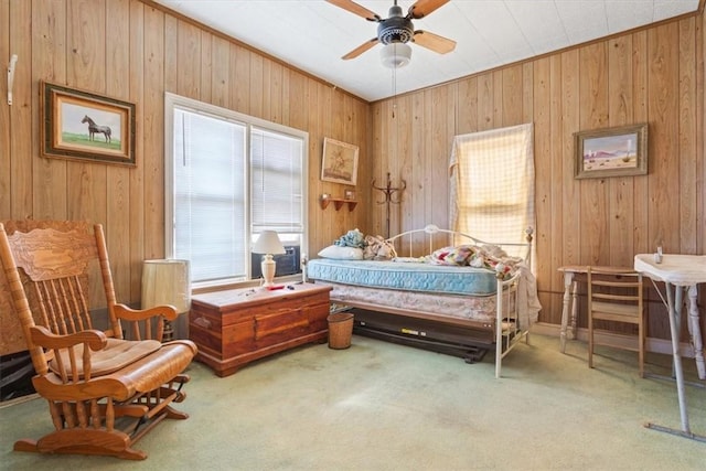 carpeted bedroom featuring crown molding, wooden walls, and ceiling fan