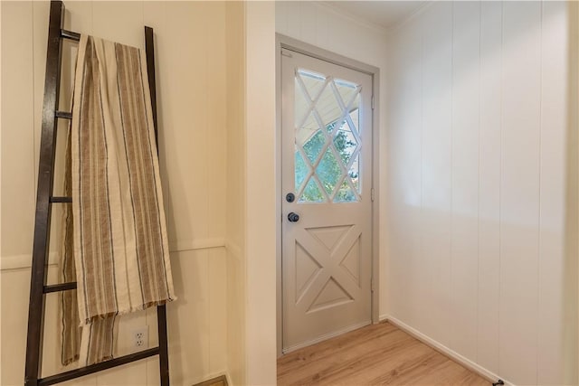 doorway with ornamental molding and light wood-type flooring