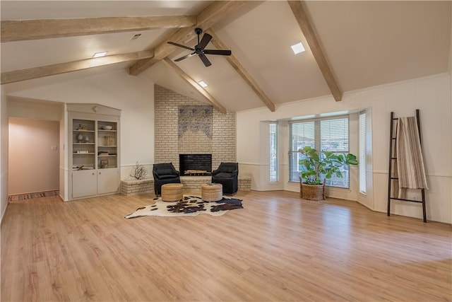 living area with a fireplace, ceiling fan, light hardwood / wood-style flooring, and lofted ceiling with beams