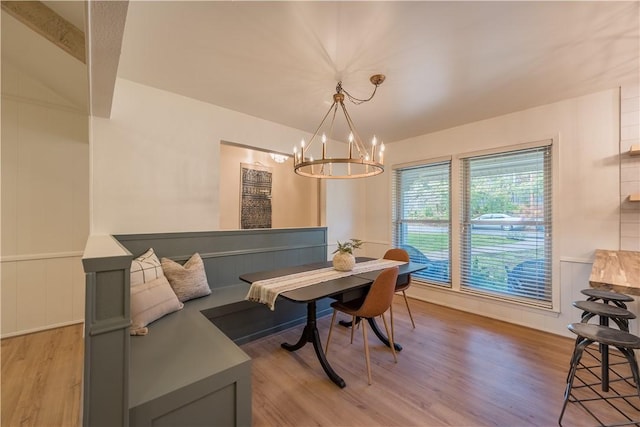 dining area featuring a chandelier, beam ceiling, and light hardwood / wood-style flooring