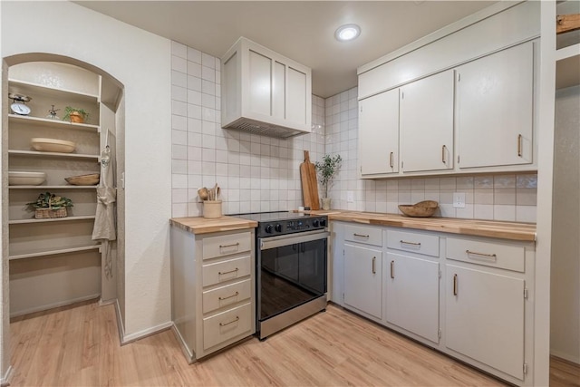 kitchen featuring butcher block counters, stainless steel range oven, light hardwood / wood-style floors, decorative backsplash, and white cabinets