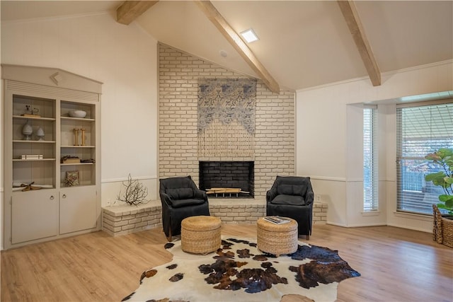 sitting room featuring vaulted ceiling with beams, light hardwood / wood-style floors, and a brick fireplace