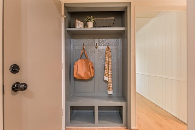 mudroom with hardwood / wood-style floors and wooden walls