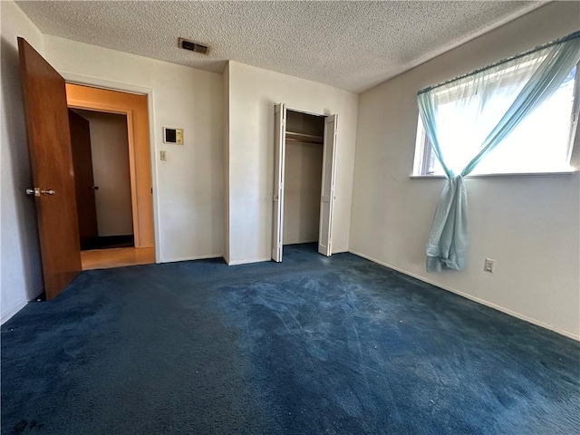 unfurnished bedroom with dark colored carpet and a textured ceiling