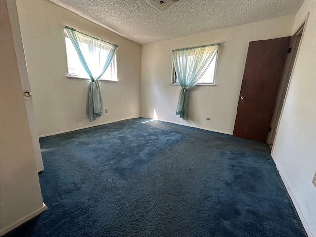 carpeted empty room with a textured ceiling