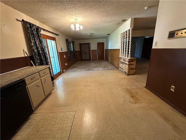 kitchen with dishwasher, a textured ceiling, a chandelier, and wooden walls